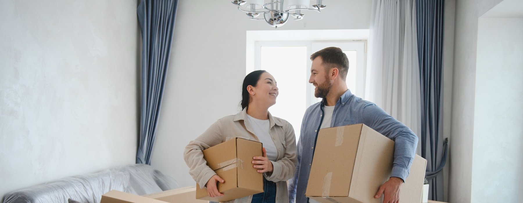 Smiling couple carrying moving boxes into their new apartment